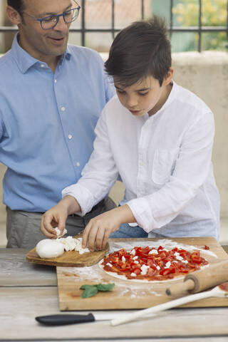 Vater und Sohn bereiten gemeinsam eine Pizza zu, lizenzfreies Stockfoto
