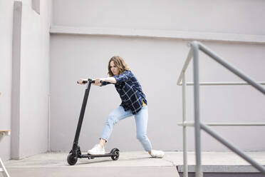 Young woman with electric scooter in a loft - JOSF03359