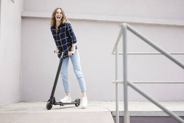 Young woman with electric scooter in a loft - JOSF03360