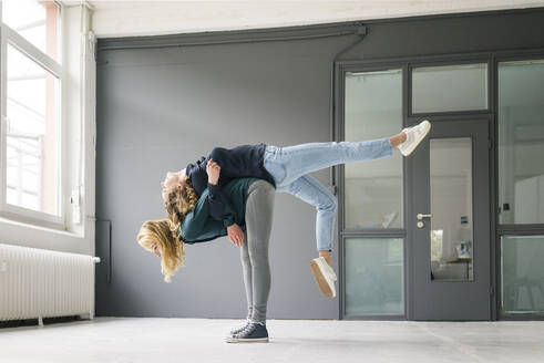 Two young women supporting each other playfully - JOSF03377