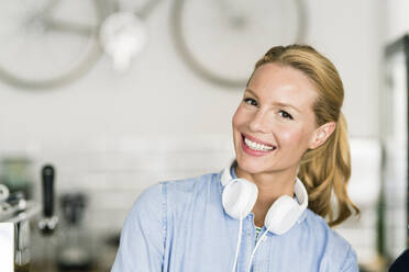 Blond woman in coffee shop with headphones - JOSF03384