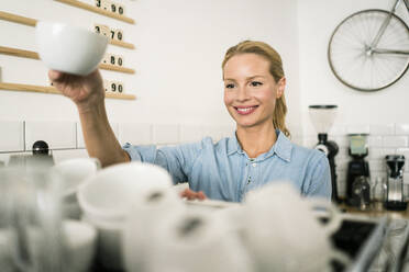 Blonde Frau arbeitet an der Theke eines Cafés - JOSF03388