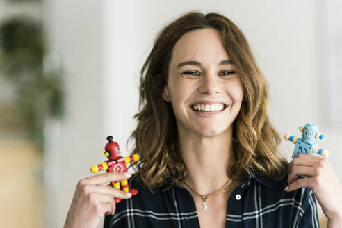 Lachende Frau mit männlichen und weiblichen Spielzeugrobotern - JOSF03392