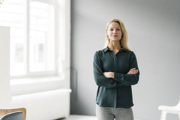 Successful, blond businesswoman standing in bright room, with arms crossed - JOSF03395