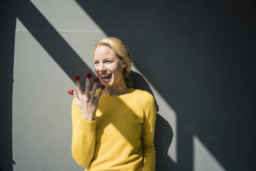 Blonde Frau mit Himbeeren an ihren Fingern, lachend - JOSF03408