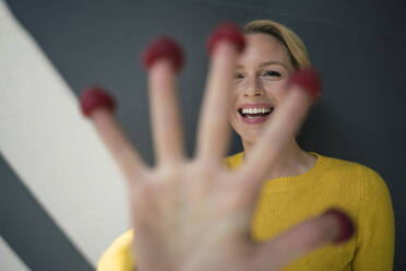 Blond woman with raspberries on her fingers, laughing - JOSF03410
