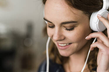 Young woman in coffee shop listening music with headphones - JOSF03445