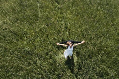 Aerial view of pregnant bride with her husband on a meadow - HMEF00485