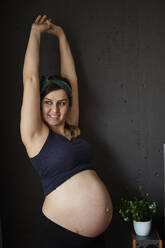 Pregnant woman showing her baby bell, stretching arms - BZF00491
