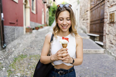 Porträt einer lächelnden jungen Frau mit Eiswaffel - GIOF06567