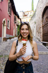 Portrait of happy young woman with ice cream cone - GIOF06569