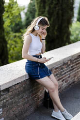 Young woman listening music with headphones and smartphone - GIOF06579