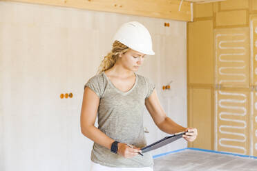 Junge Frau, die den Bau eines neuen Holzhauses kontrolliert - TCF06132