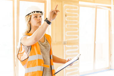 Young woman checking the construction of a new wooden house - TCF06137