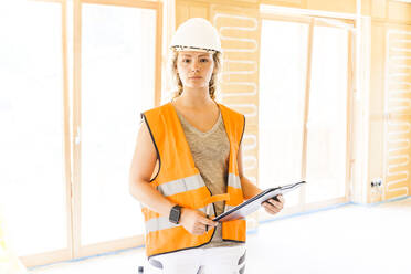 Young woman checking the construction of a new wooden house - TCF06138