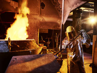 Arbeiter hält Metallstab im Ofen einer Gießerei - CVF01236