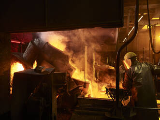 Rückansicht eines Arbeiters, der in einer Gießerei am Ofen arbeitet - CVF01237