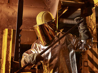 Männlicher Arbeiter hält Metallstange in Gießerei - CVF01241