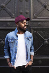 Portrait of mid adult man wearing jeans jacket and basecap - IGGF01227