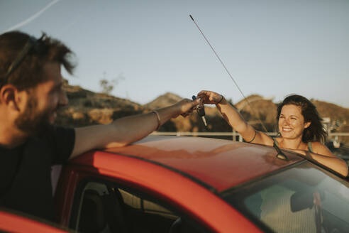 Couple exchanging car keys on a road trip - DMGF00072