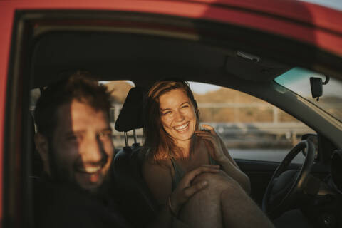 Glückliches Paar auf einer Autoreise mit Blick aus dem Autofenster, lizenzfreies Stockfoto