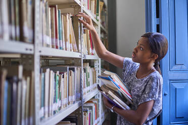 Junge Frau prüft die Bücher in den Regalen der Nationalbibliothek, Maputo, Mocambique - VEGF00392