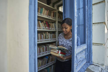 Junge Frau beim Prüfen von Büchern in der Nationalbibliothek, Maputo, Mocambique - VEGF00395