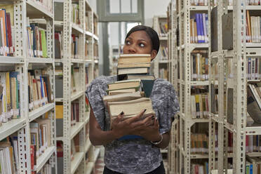 Junge Frau mit einem Stapel Bücher in der Nationalbibliothek, Maputo, Mocambique - VEGF00396