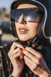 Porträt eines Motorradfahrers mit Sonnenbrille, der seinen Helm aufsetzt - LJF00295