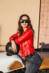 Portrait of motorcyclist wearing sunglasses and red leather jacket - LJF00302