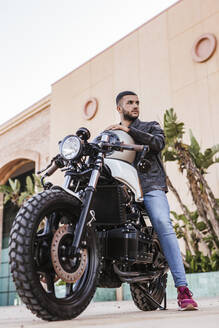 Porträt eines jungen Mannes, der auf seinem Motorrad sitzt - LJF00328
