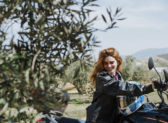 Portrait of happy redheaded woman on motorbike, Andalusia, Spain - LJF00333