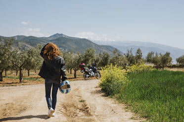 Rückansicht eines rothaarigen Motorradfahrers auf einer unbefestigten Straße, Andalusien, Spanien - LJF00341