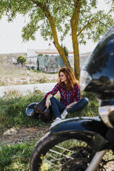 Motorcyclist having cigarette break under a tree - LJF00349