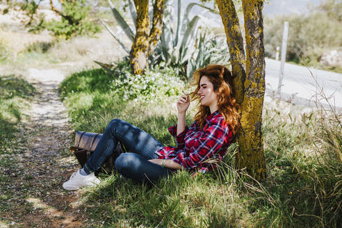 Rothaarige Frau mit Zigarettenpause unter einem Baum - LJF00350