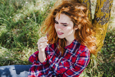 Portrait of redheaded woman having cigarette break under a tree - LJF00351