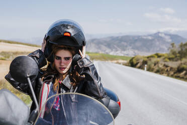 Portrait of motorcyclist putting helmet on, Andalusia, Spain - LJF00361