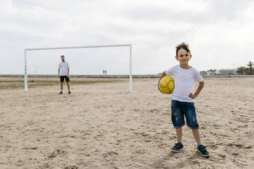 Porträt eines Jungen mit Fußball am Strand - JRFF03413