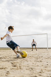 Mann und Junge spielen Fußball am Strand - JRFF03415