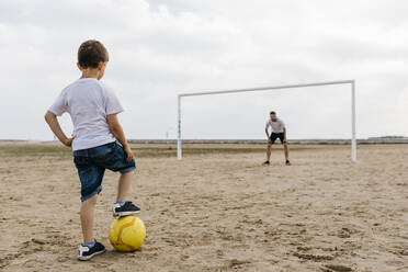 Man and boy playing soccer on the beach - JRFF03416