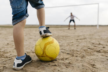 Close-up of man and boy playing soccer on the beach - JRFF03417