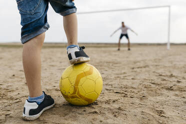 Nahaufnahme eines Mannes und eines Jungen beim Fußballspielen am Strand - JRFF03417