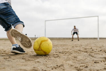 Close-up of man and boy playing soccer on the beach - JRFF03418
