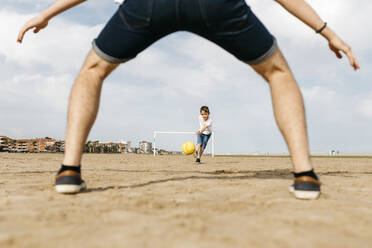 Man and boy playing soccer on the beach - JRFF03419