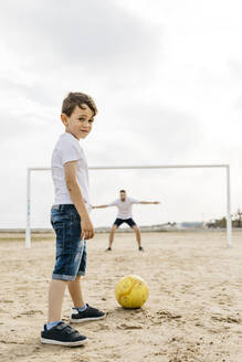 Man and boy playing soccer on the beach - JRFF03421