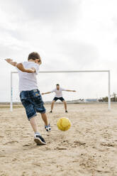 Mann und Junge spielen Fußball am Strand - JRFF03422