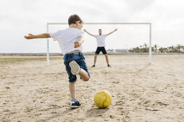 Mann und Junge spielen Fußball am Strand - JRFF03423