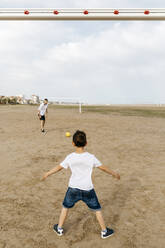 Junge und Mann spielen Fußball am Strand - JRFF03427