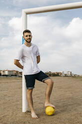 Porträt eines Mannes mit Fußball am Strand - JRFF03431