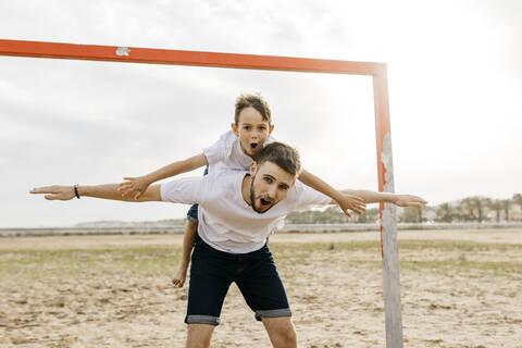 Mann und Junge feiern ein Tor am Strand, lizenzfreies Stockfoto